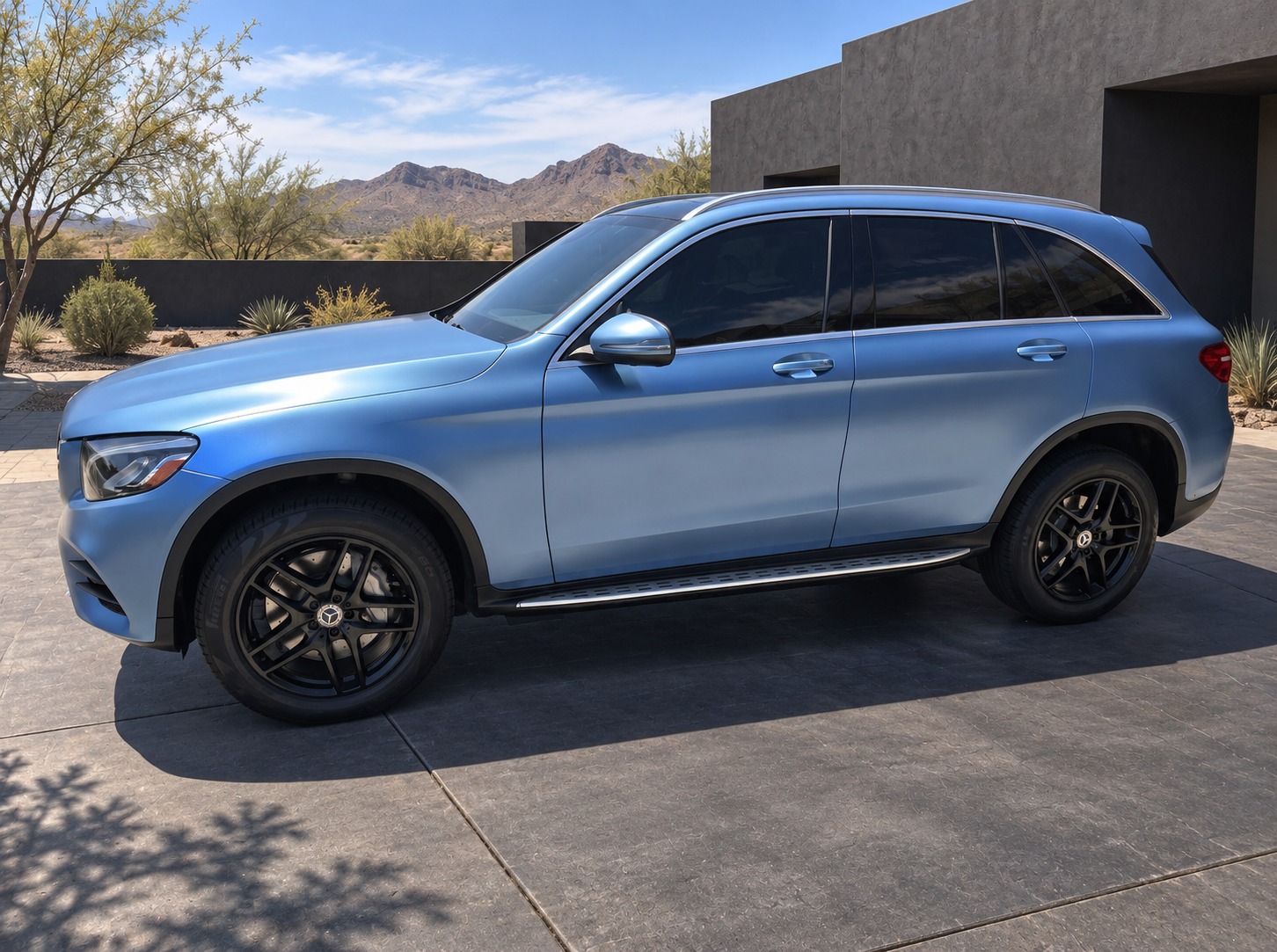 Mercedes-Benz SUV, Satin blue · Black wheels, with an edited architectural desert background